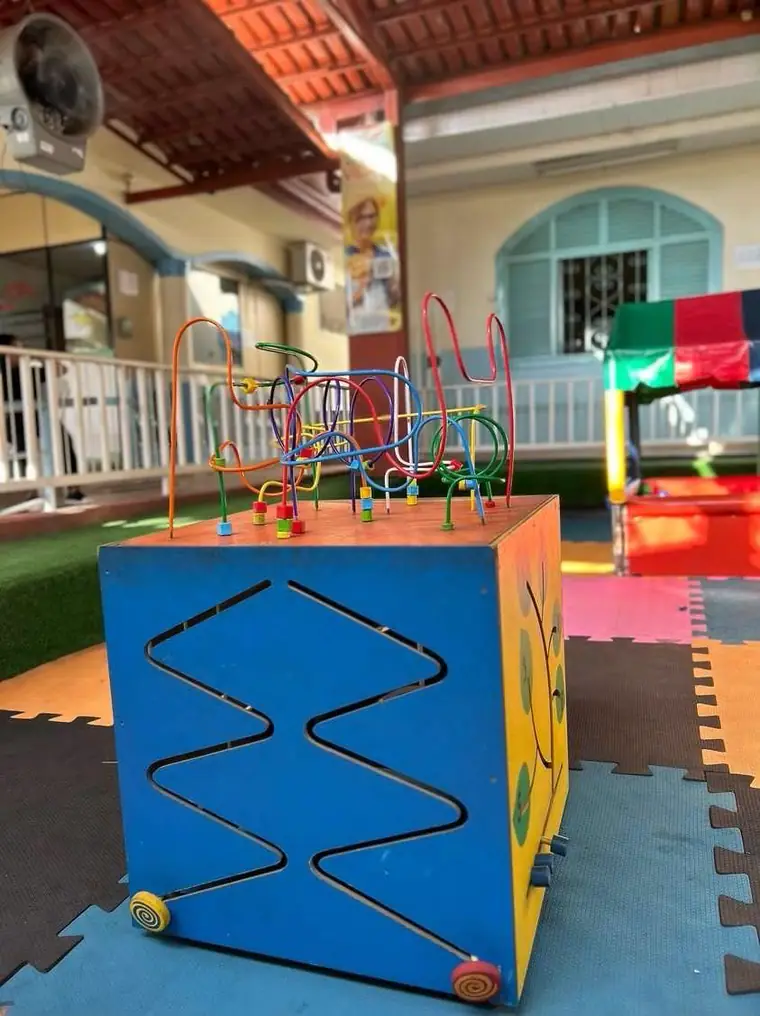 Pátio coberto com piso de borracha colorido e cubo de atividades