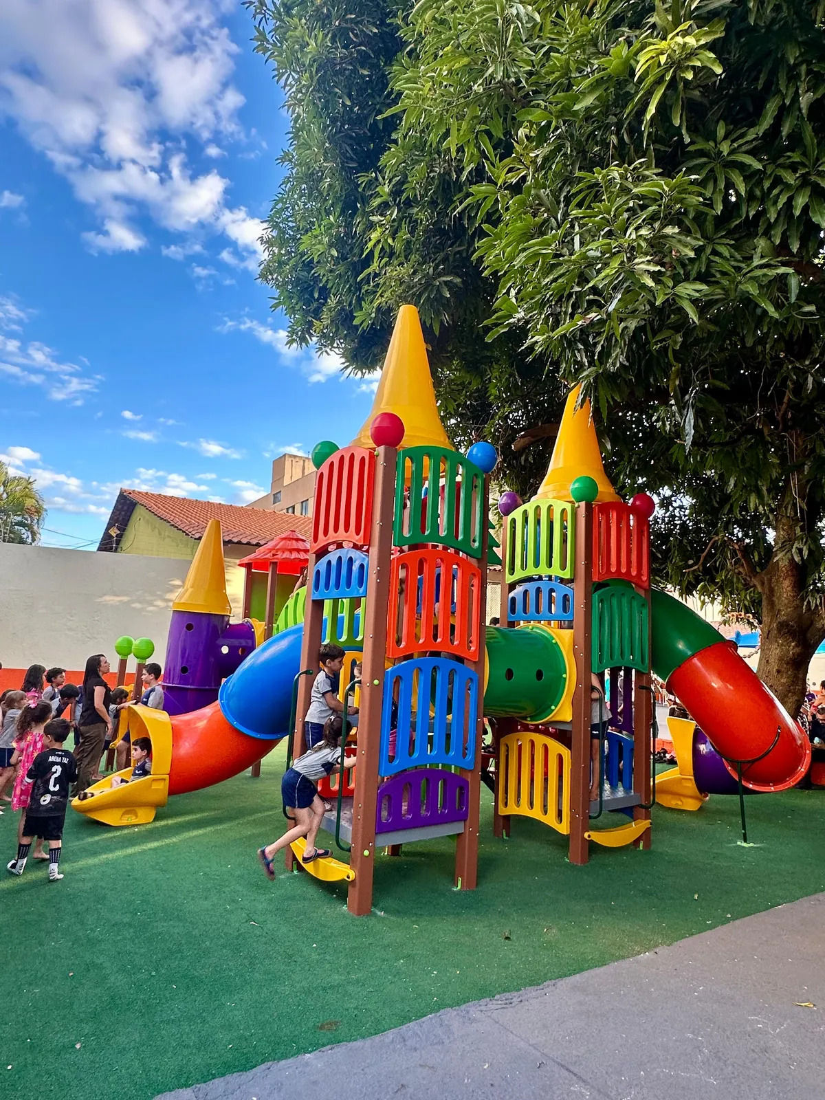 Crianças subindo e brincando no brinquedão colorido durante o recreio