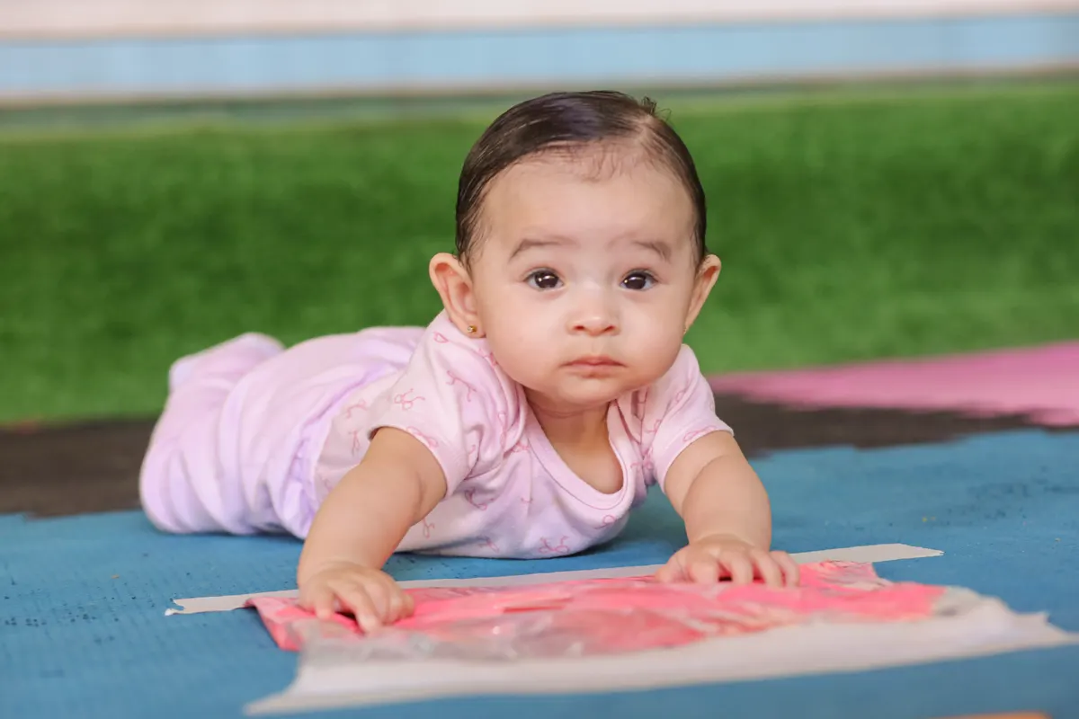 Bebê deitado no tapete explorando saquinho sensorial com tinta