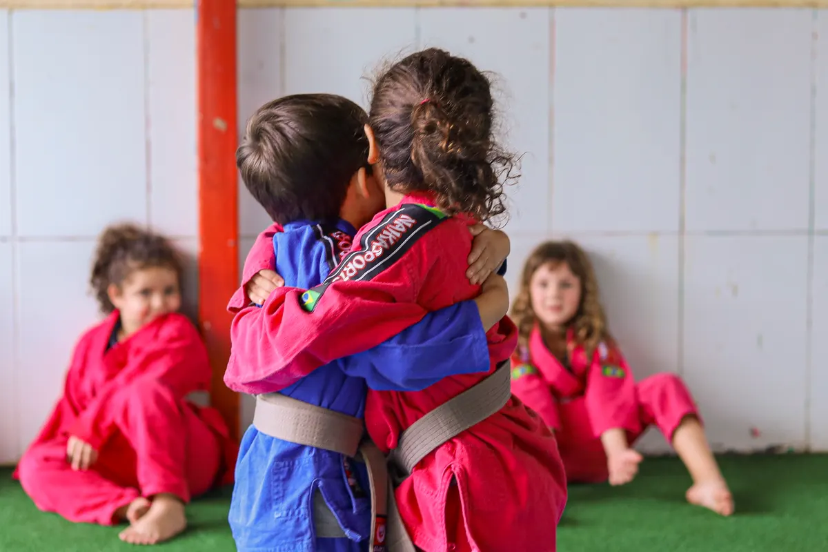 Duas crianças de quimono se abraçando na aula de judô da Criarte