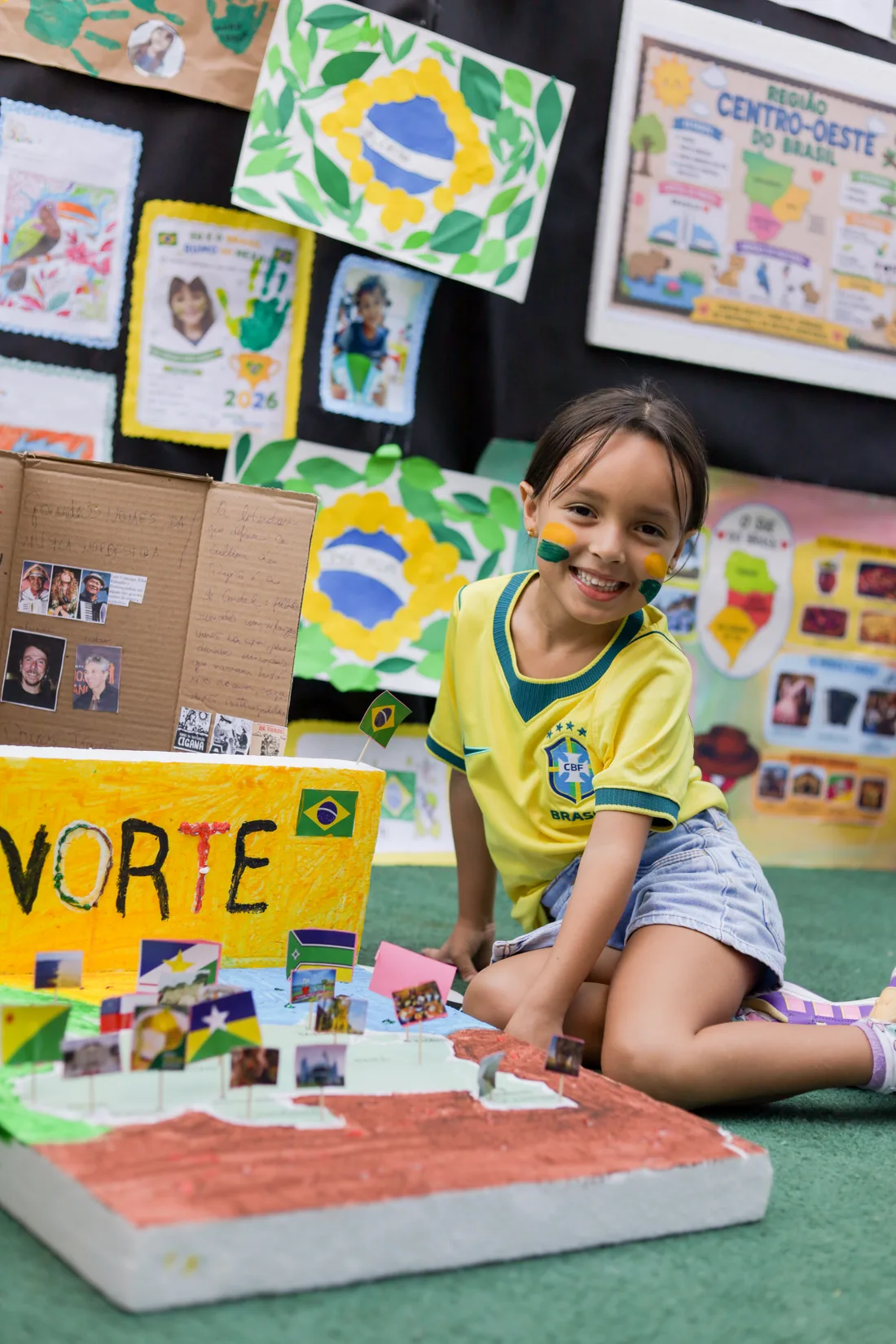 Aluna da Criarte II sorrindo ao lado da maquete que fez sobre as regiões do Brasil