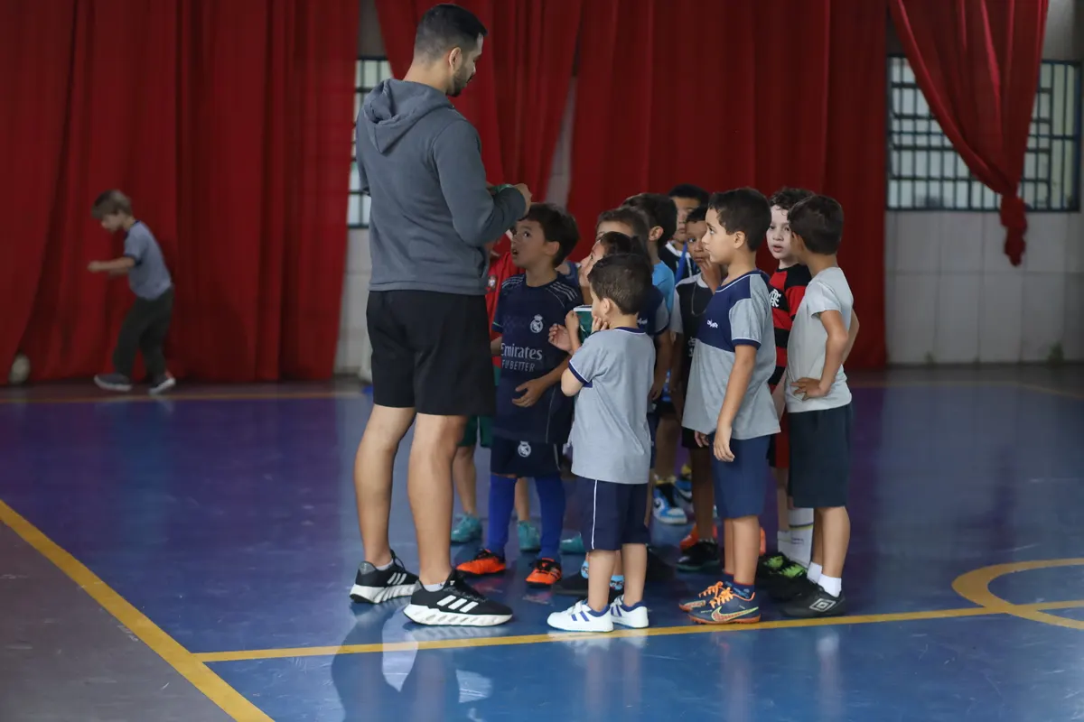 Professor de futsal reunindo os alunos na quadra da Escola Criarte