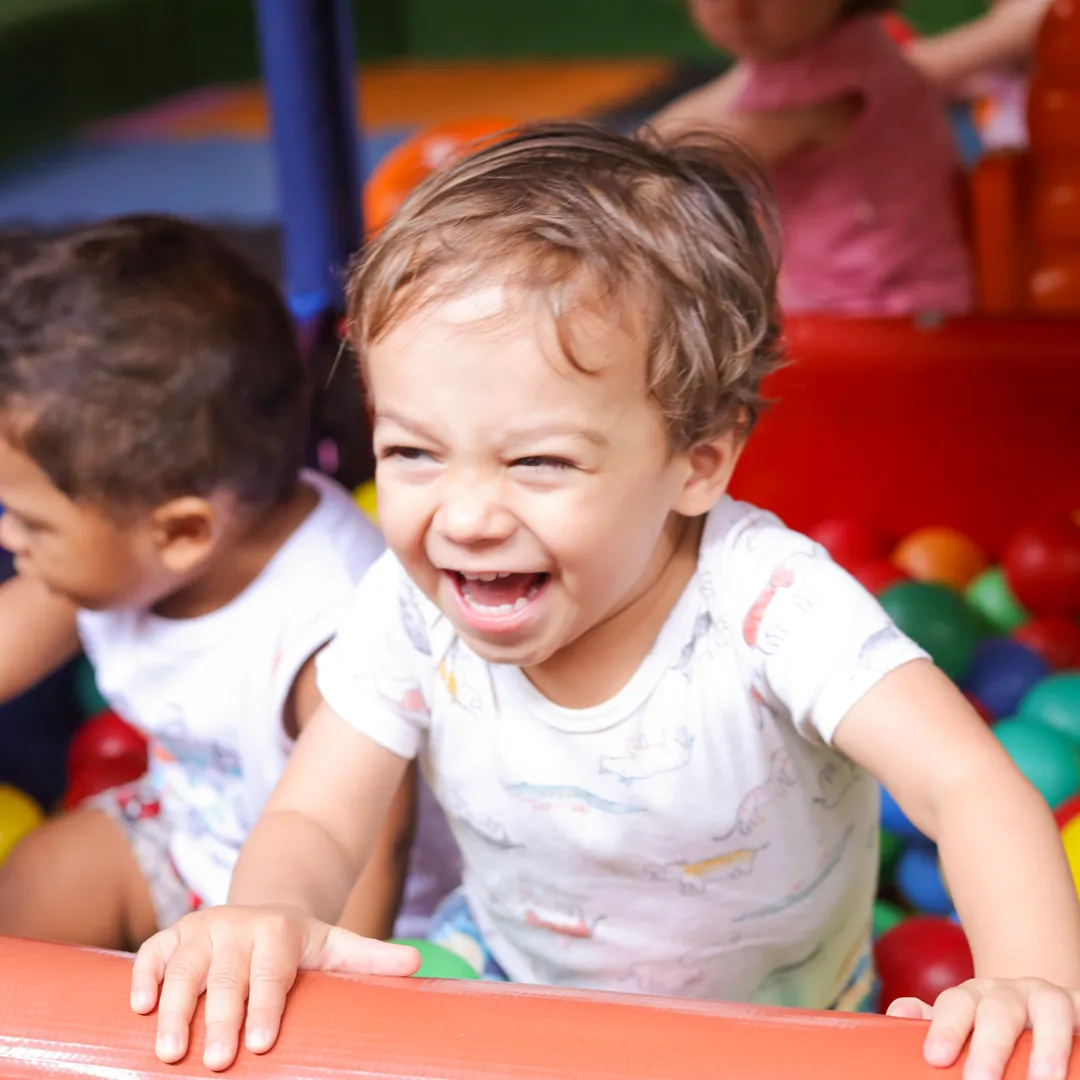 Criança sorrindo na piscina de bolinhas coloridas